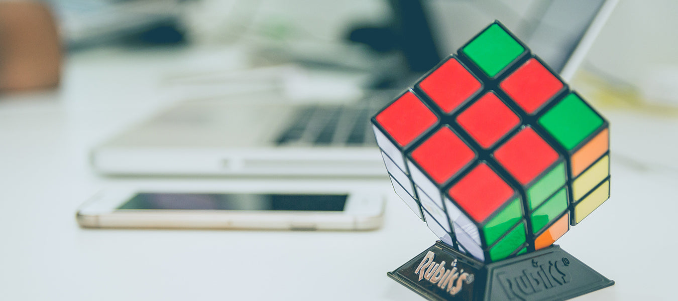 Unsolved rubick cube next to a phone and a laptop