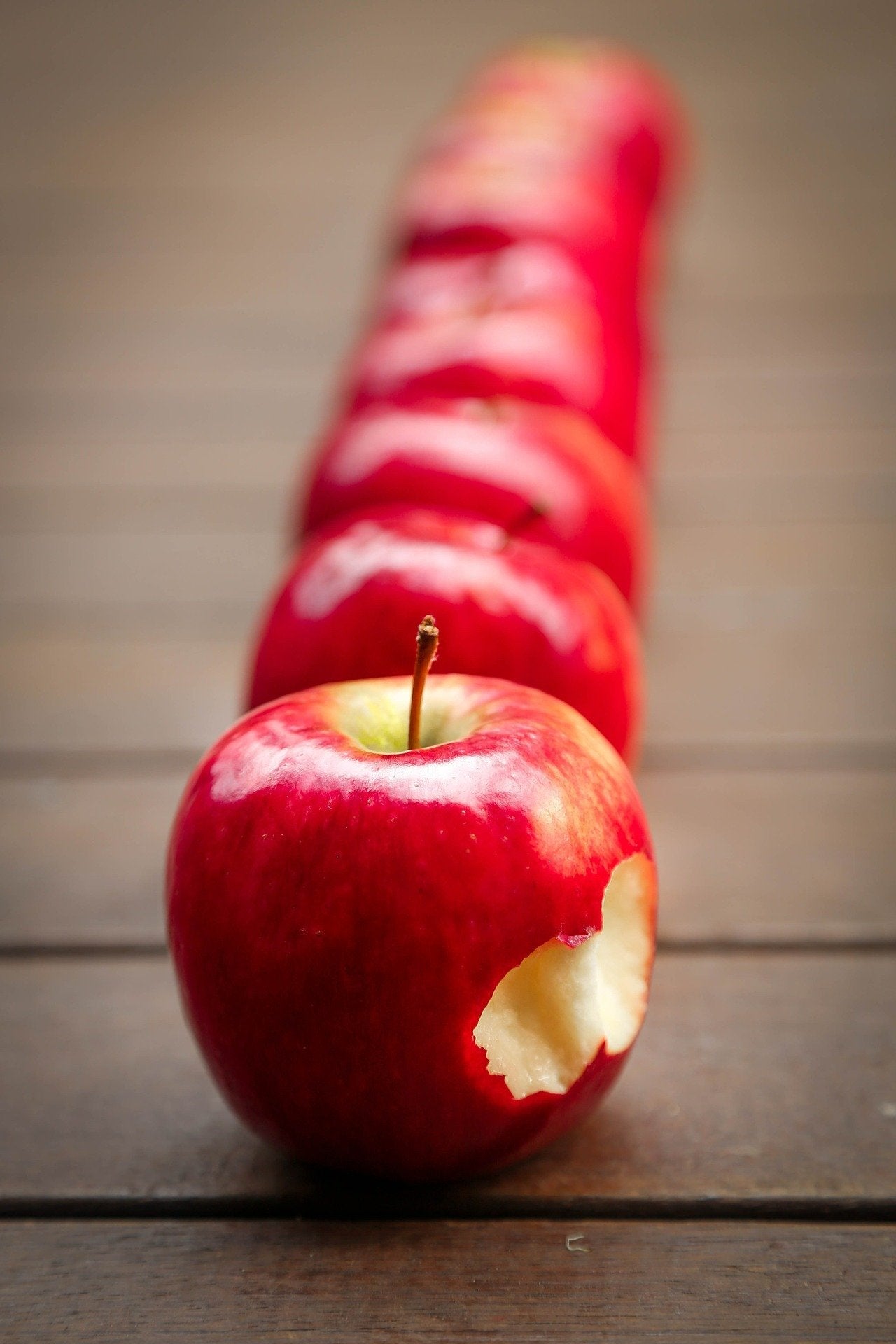 Red apples in line with the first one being bitten