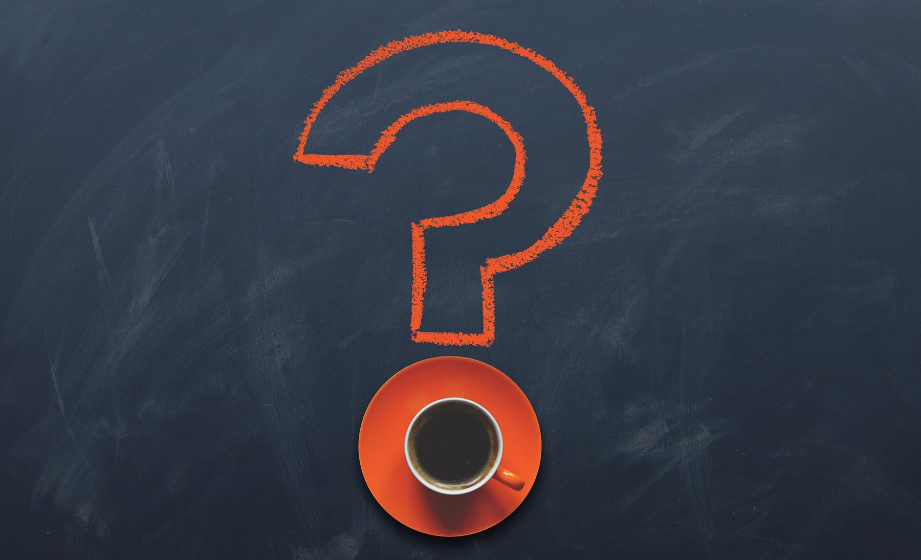 Question mark drown on a board with the dot being a cup of coffee on an orange plate