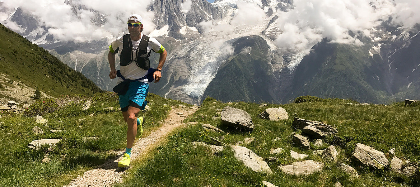 Man in blue shorts hiking and running on rocky mountain
