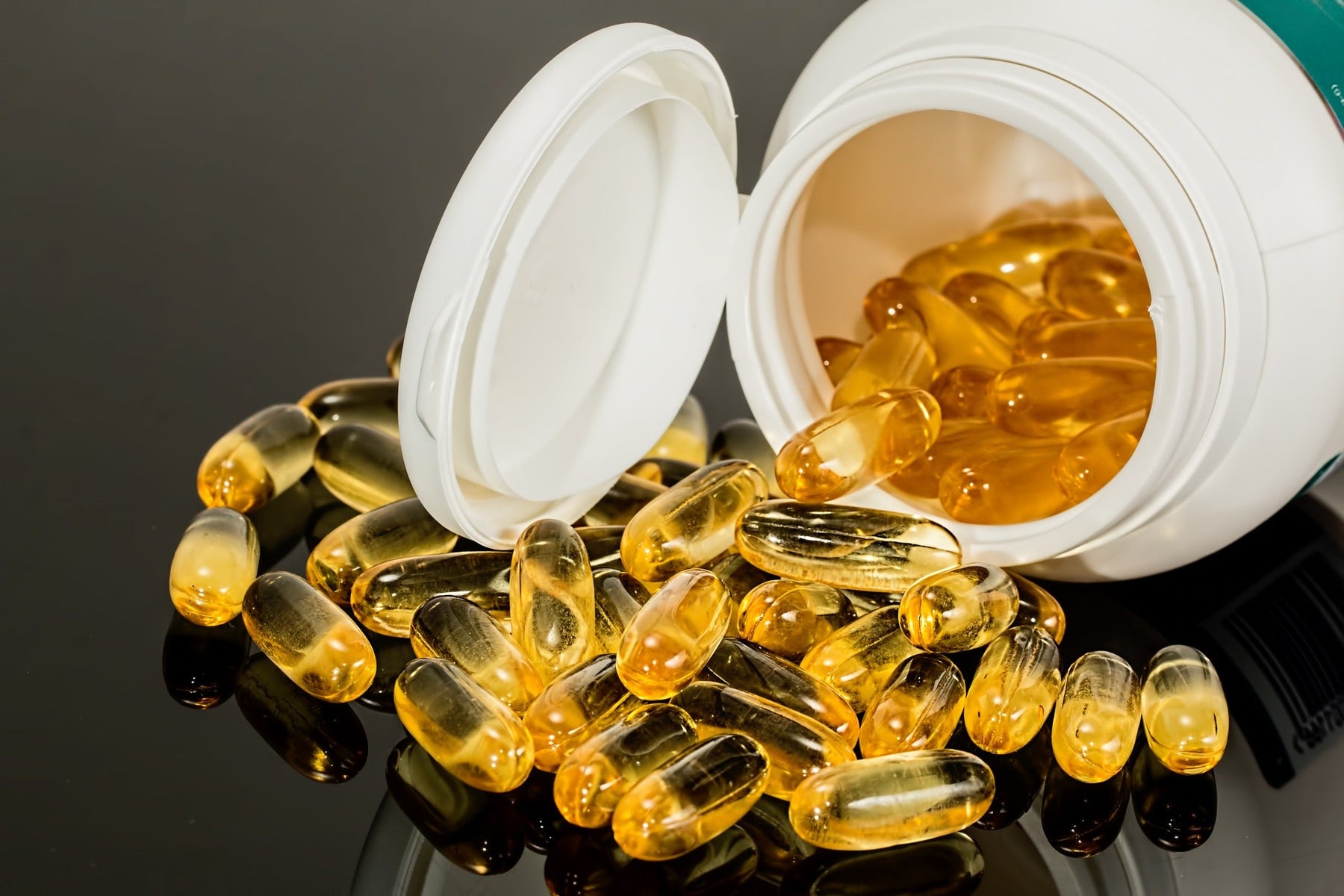 Fish oil pills dropping off a white bottle