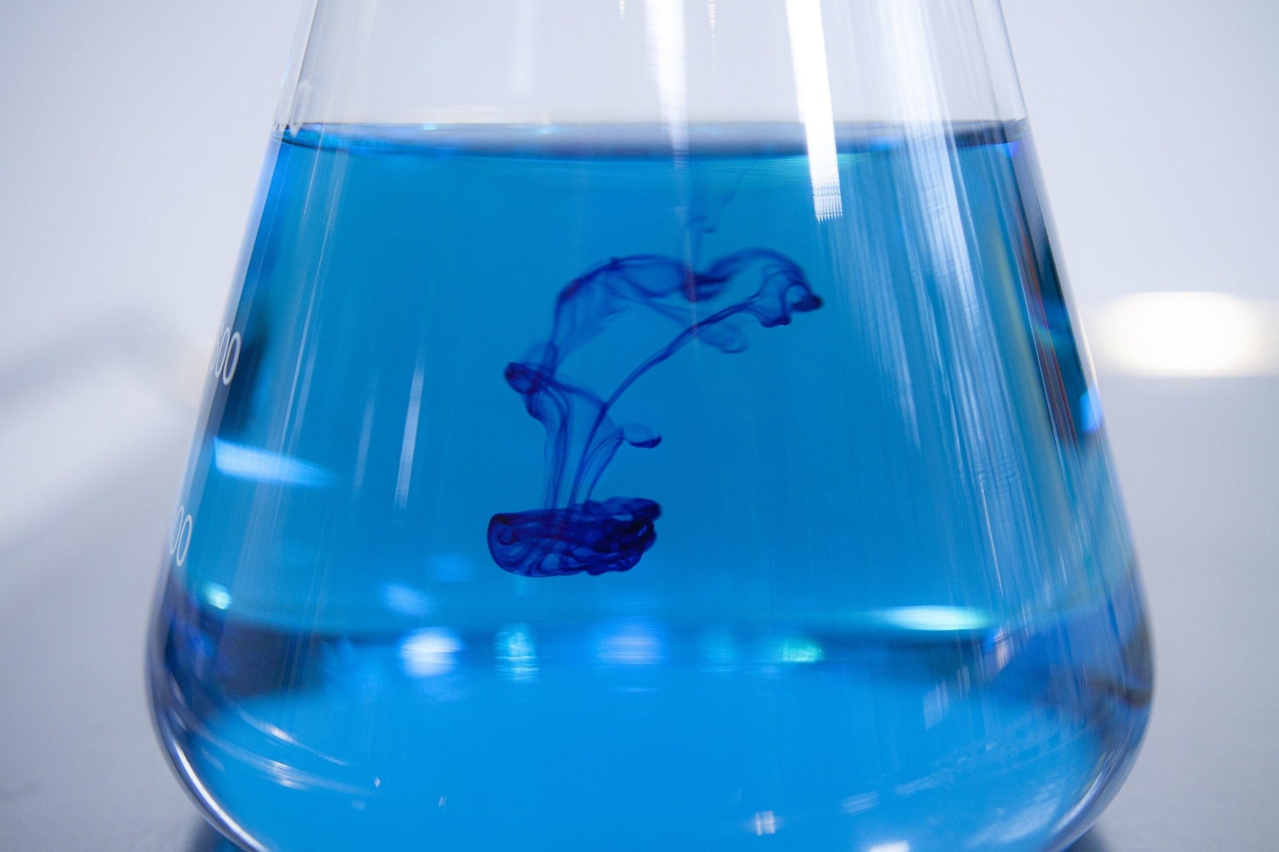 Blue liquid with blue drop in it within a glass recipient