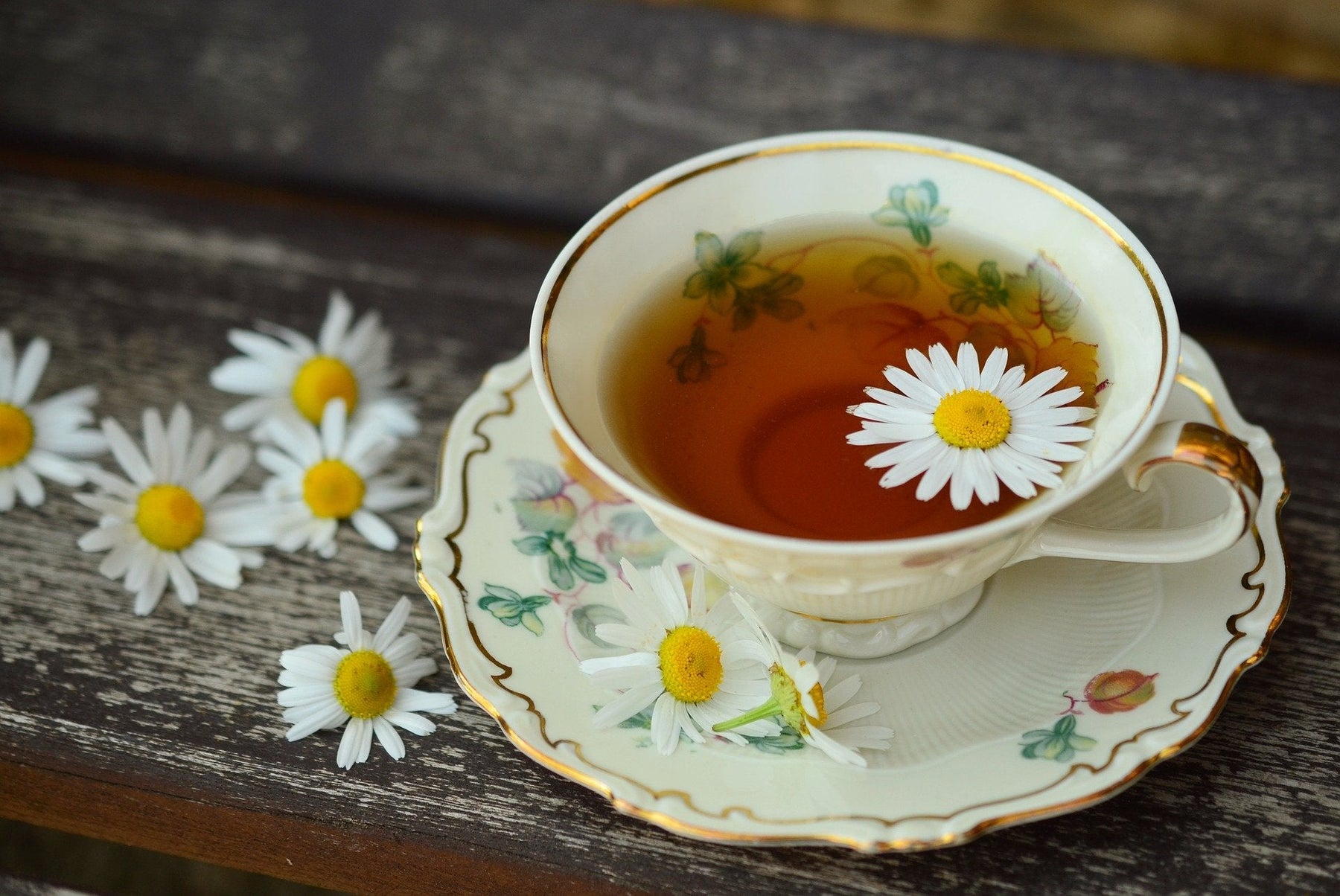 A cup of tea with flowers on a wooden surface