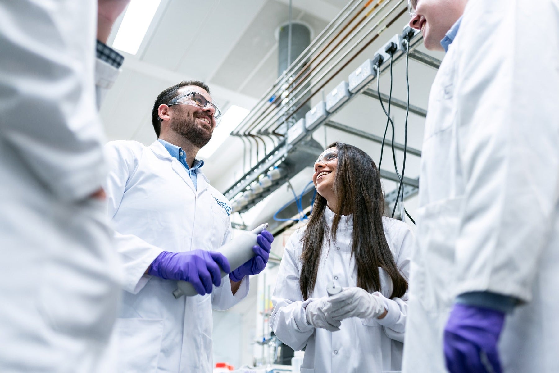 People in white with purple gloves discussing