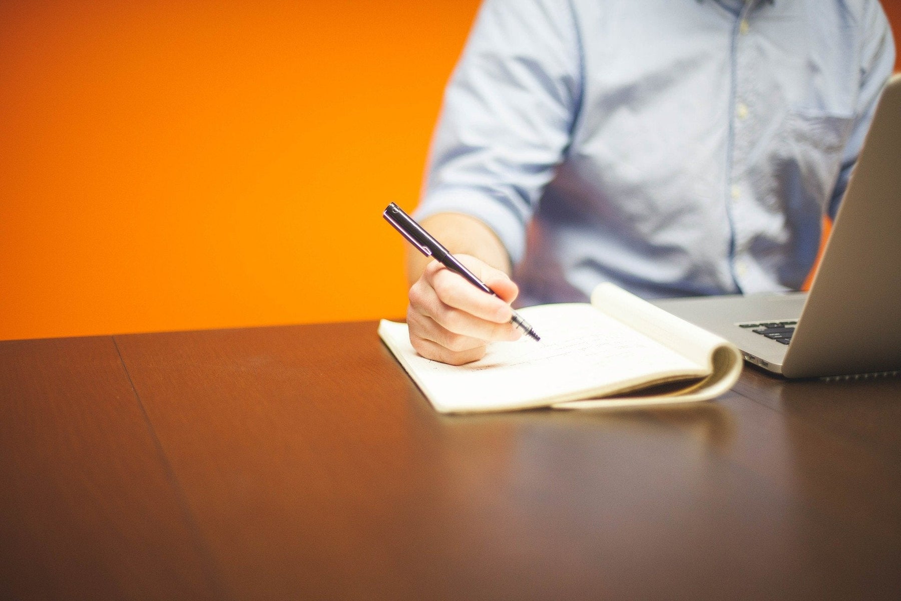 Man taking notes on a notebook over a wooden desk