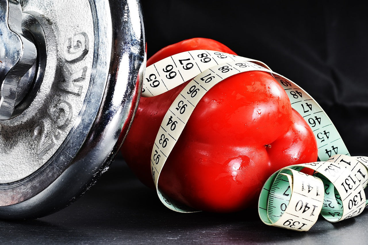 A dumbell next to a red bellpaper covered in a measurement band