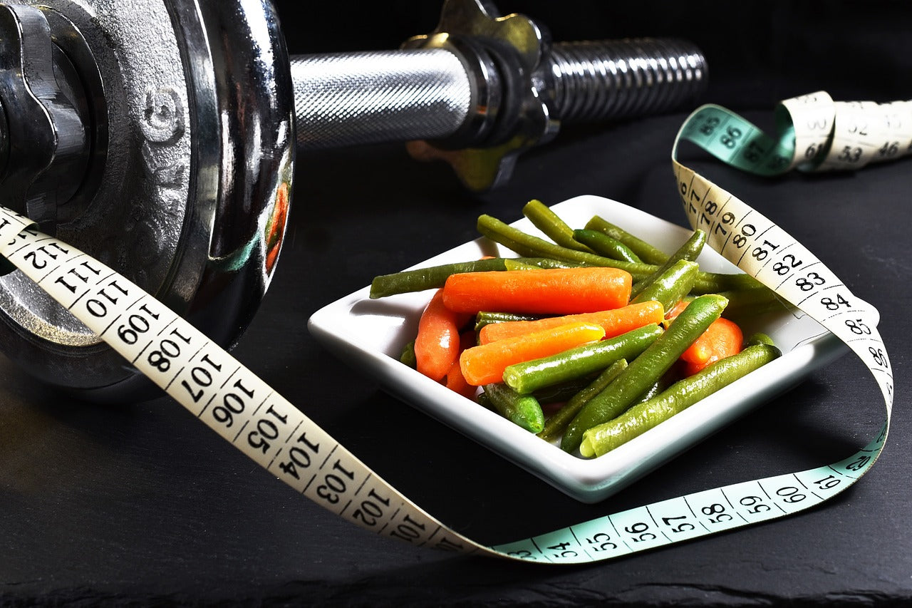 Dumbell next to a plate of vegetables and a ruler