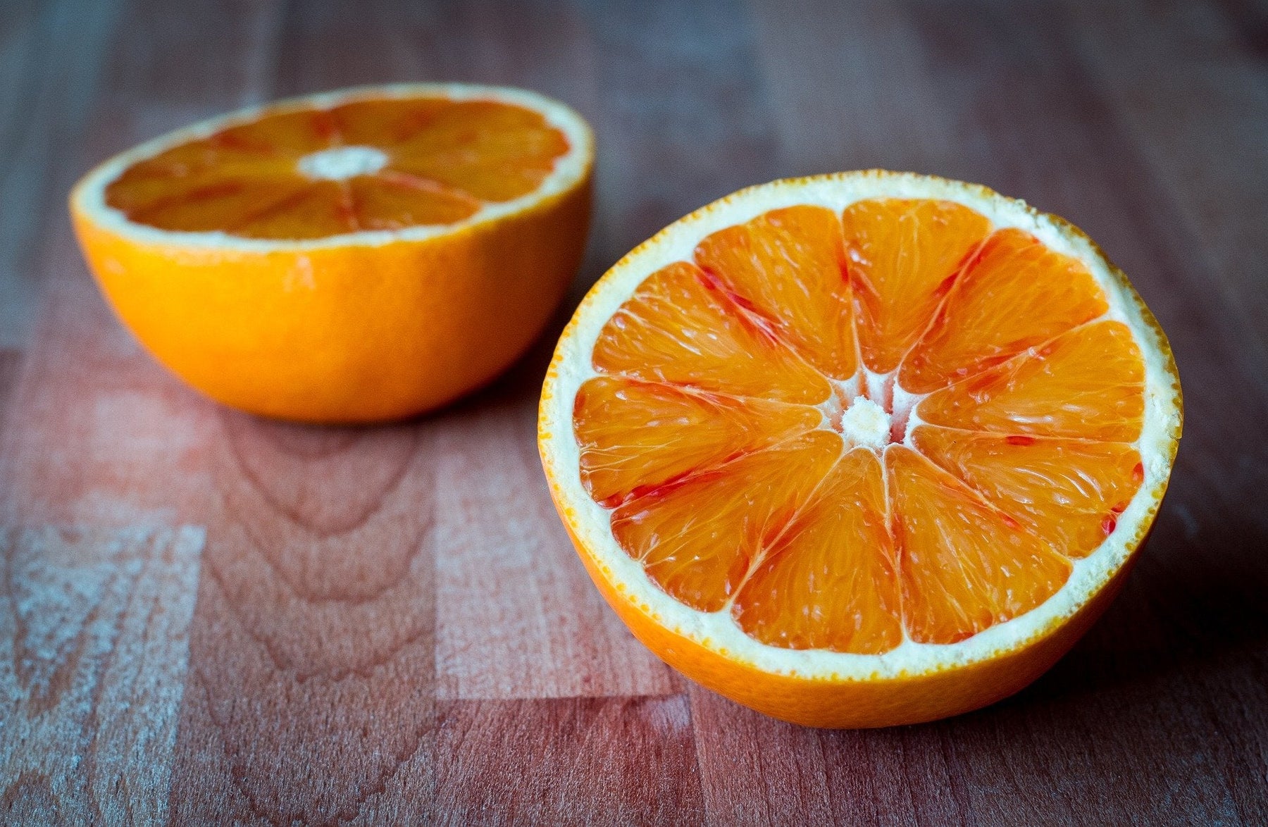 An orange cut in half over a wooden floor