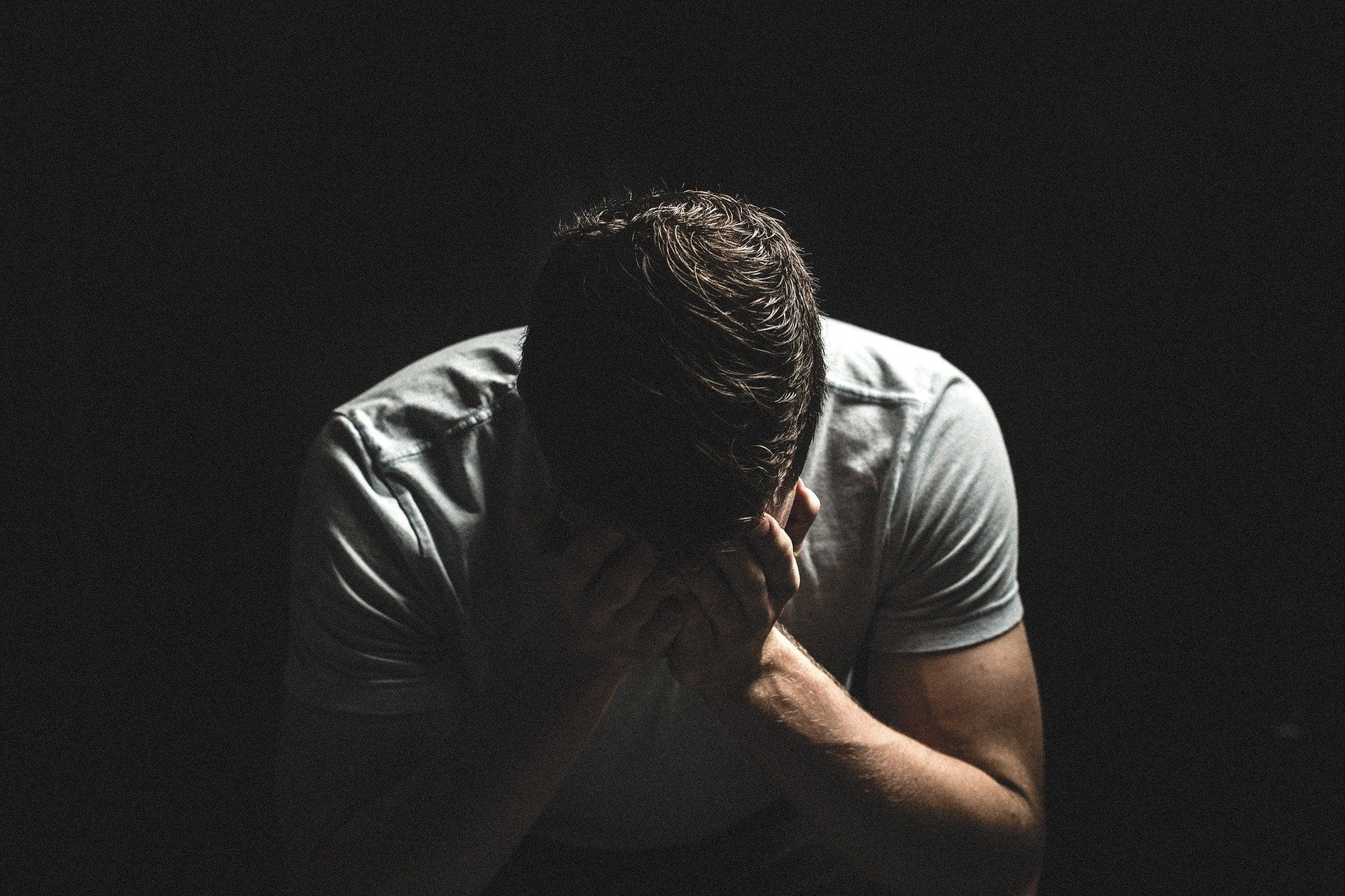 Man in a t-shirt covering face with his palms