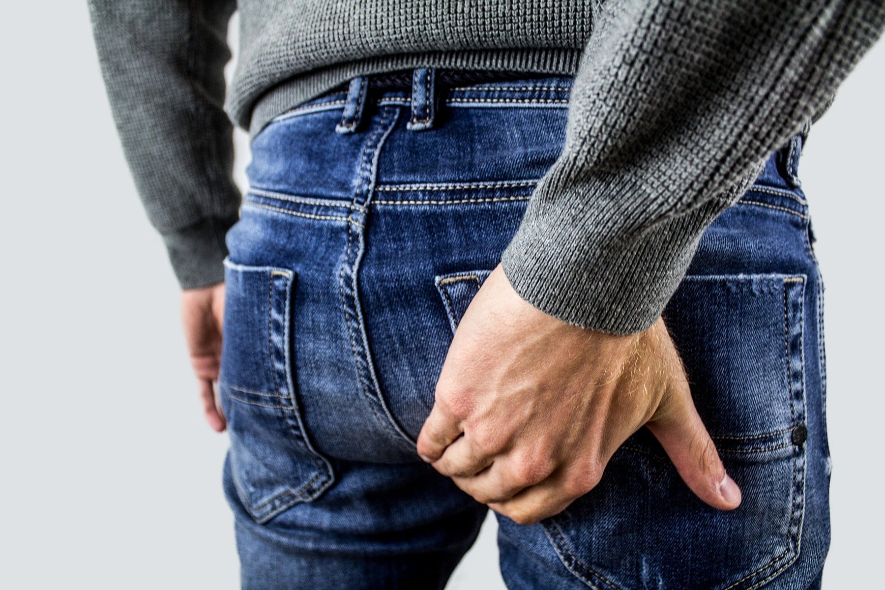 Man in blue jeans having trouble with hemorrhoids