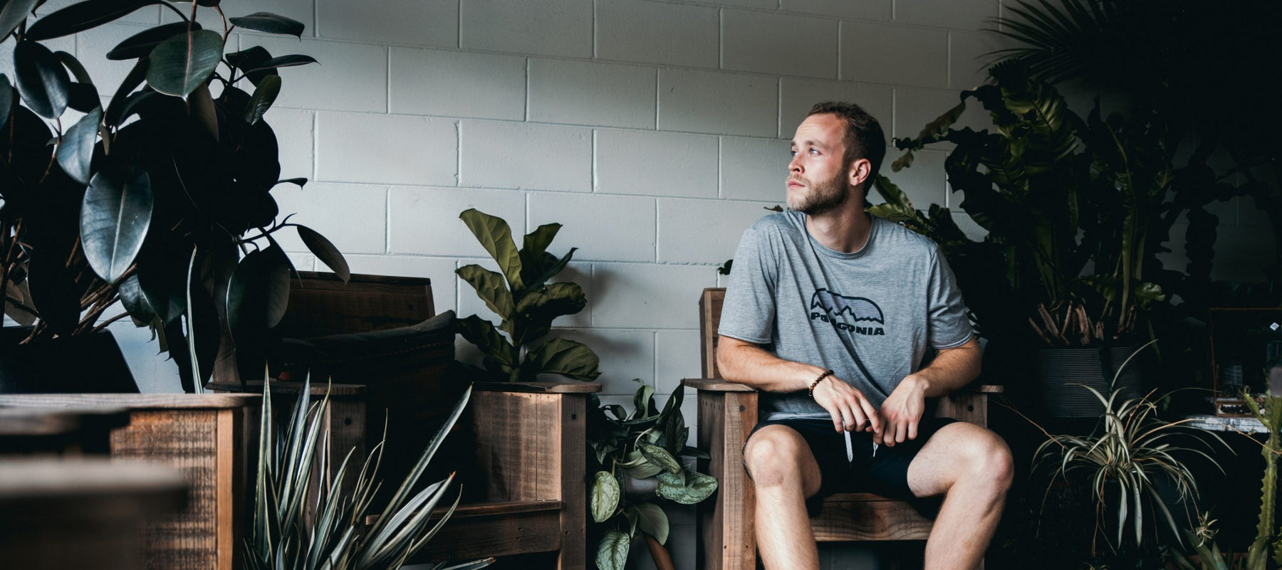 Man in shorts thinking and being surrounded by palnts