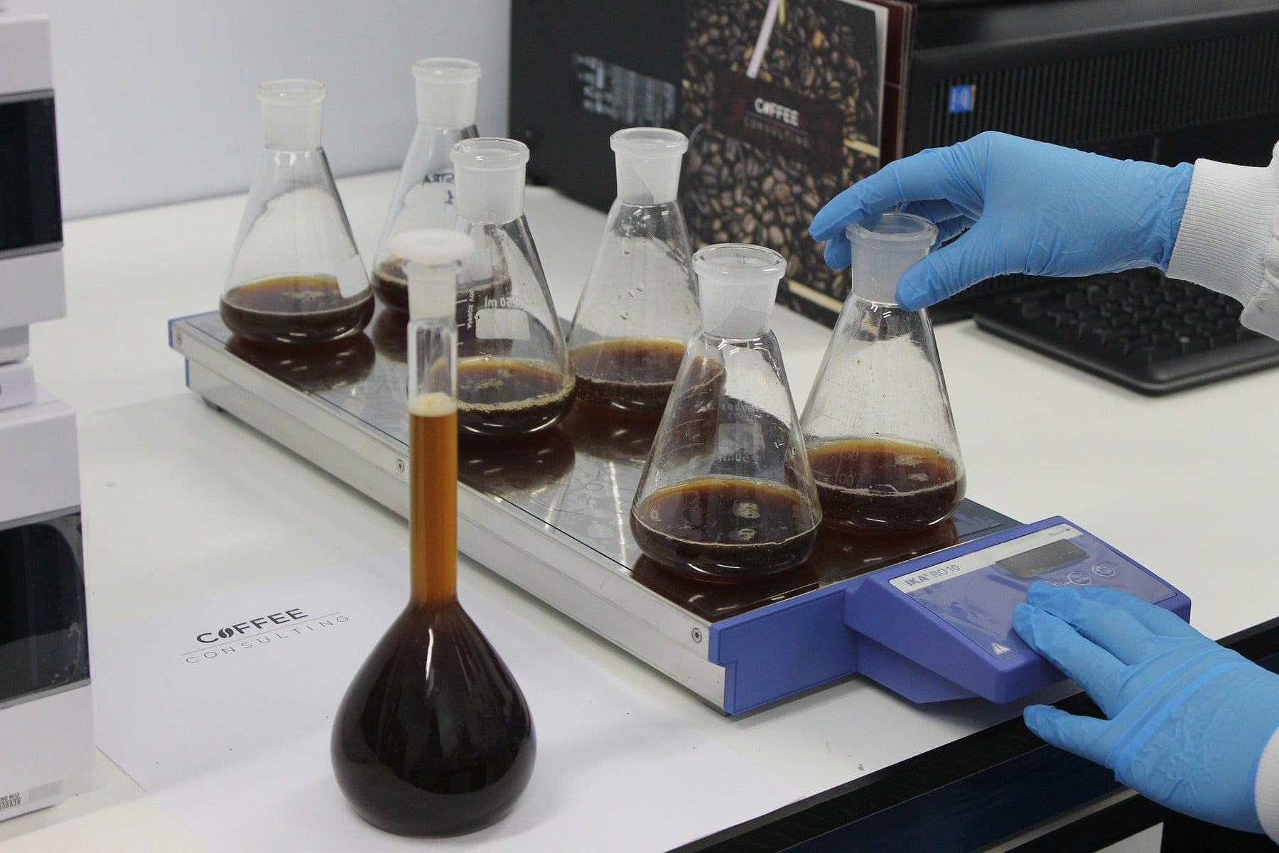 Person with gloves handling glass recipients with black liquid