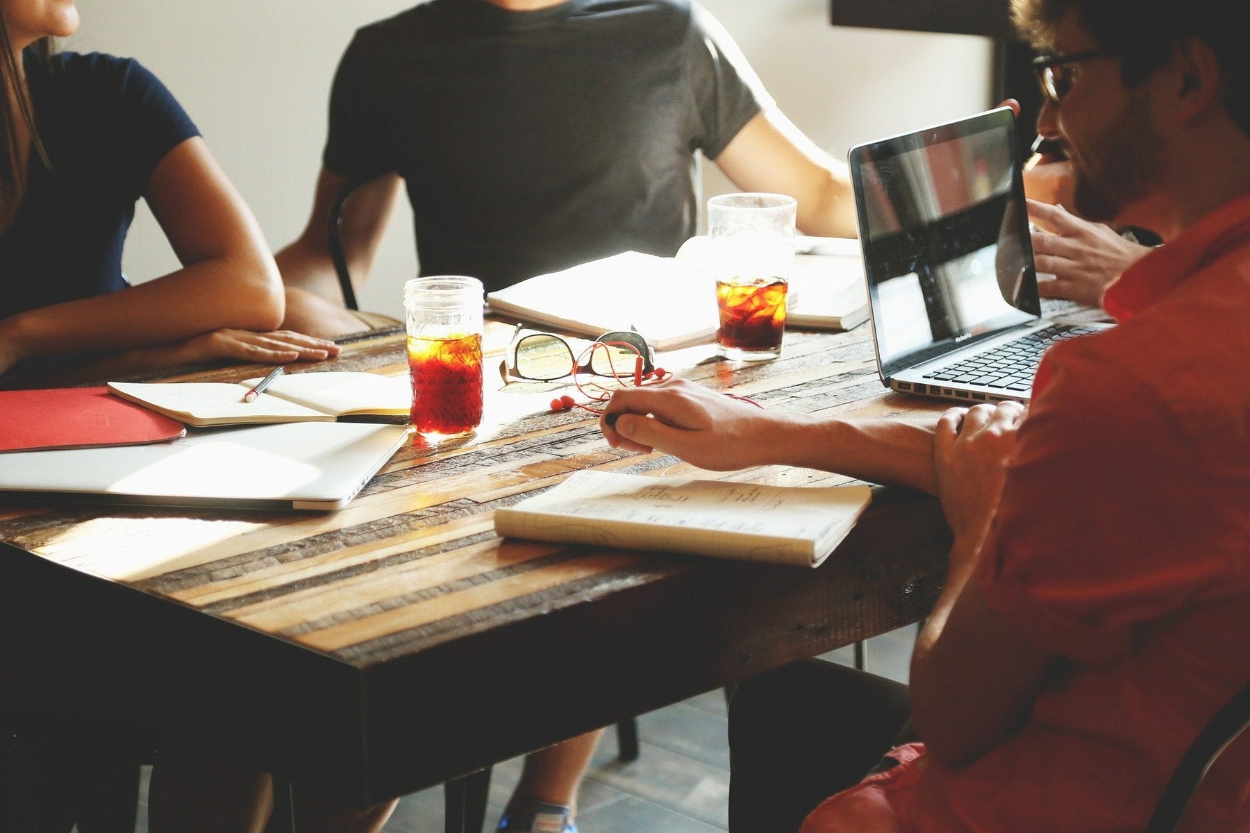 People discussing over a wooden table taking notes and drinking