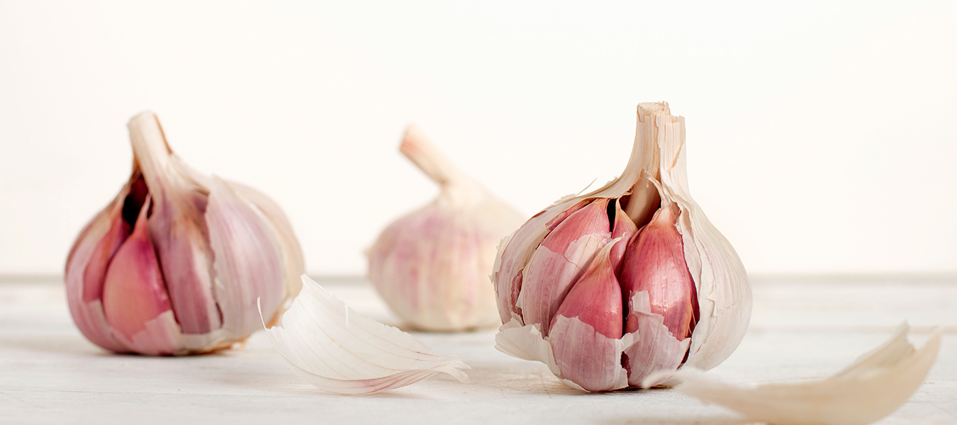Three pieces of garlic slightly pilled on a white surface