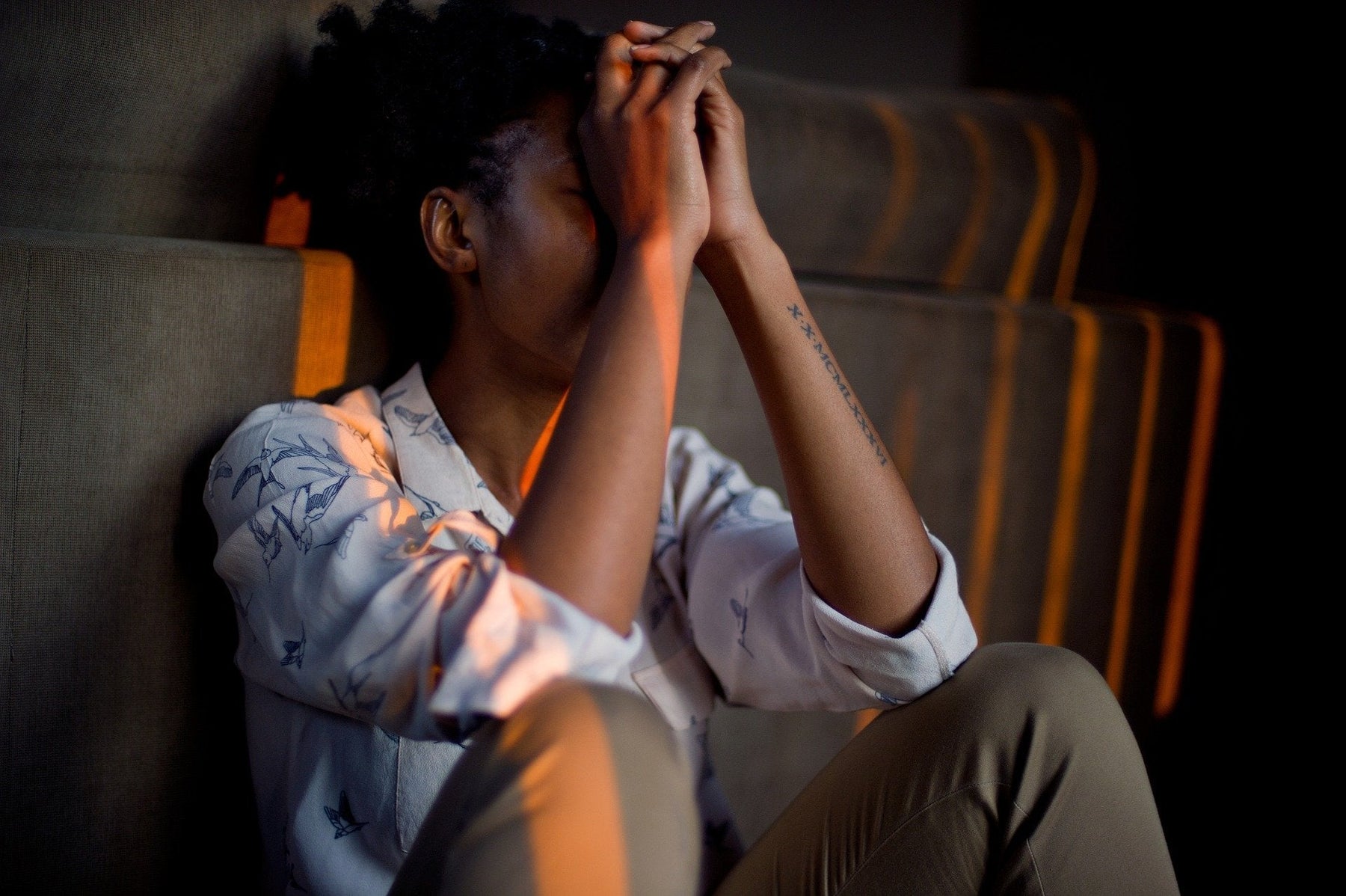 Sad woman sitting on a floor with her hands on her forehead