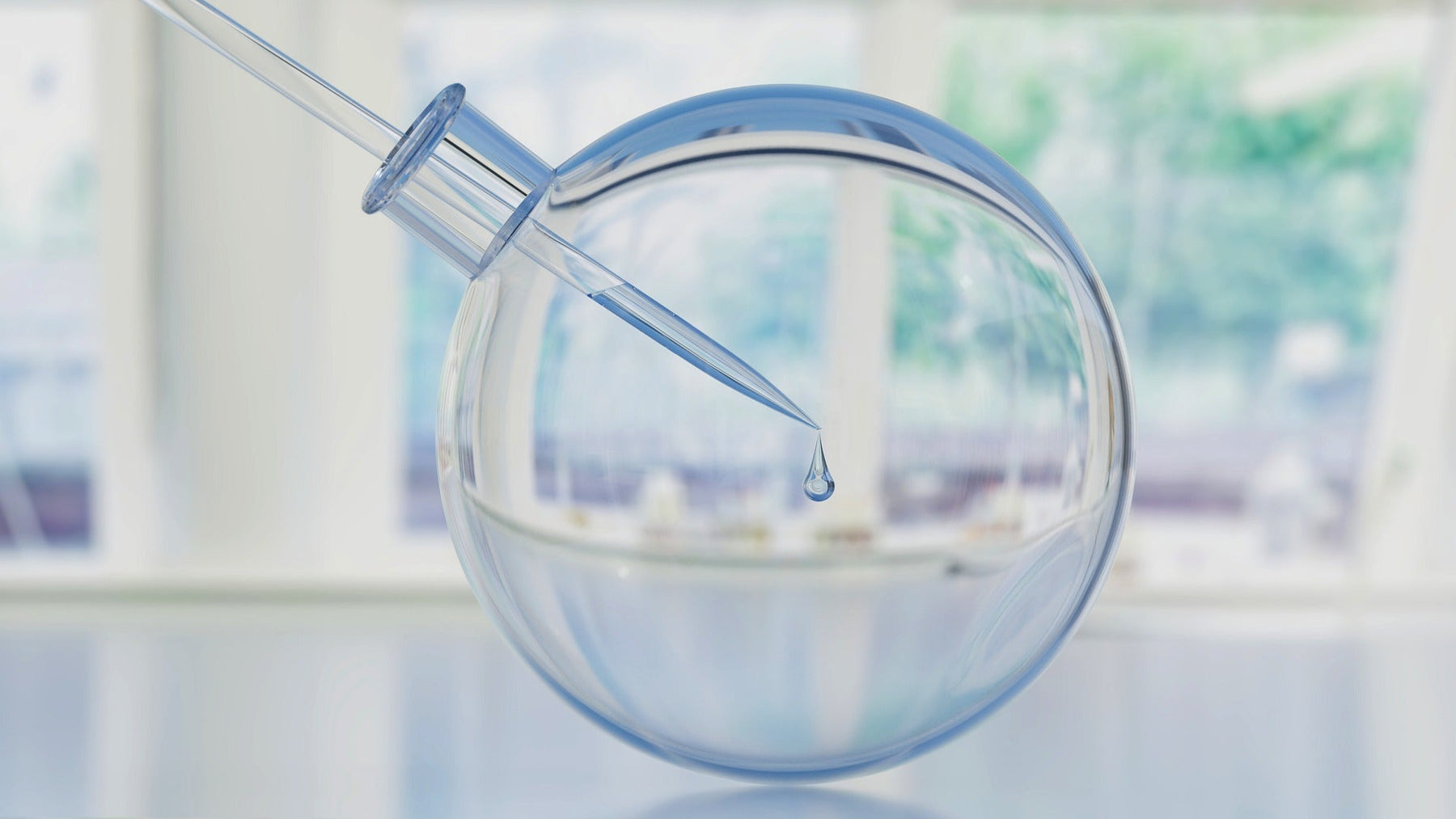 Small pipe dropping liquid in a round glass boll