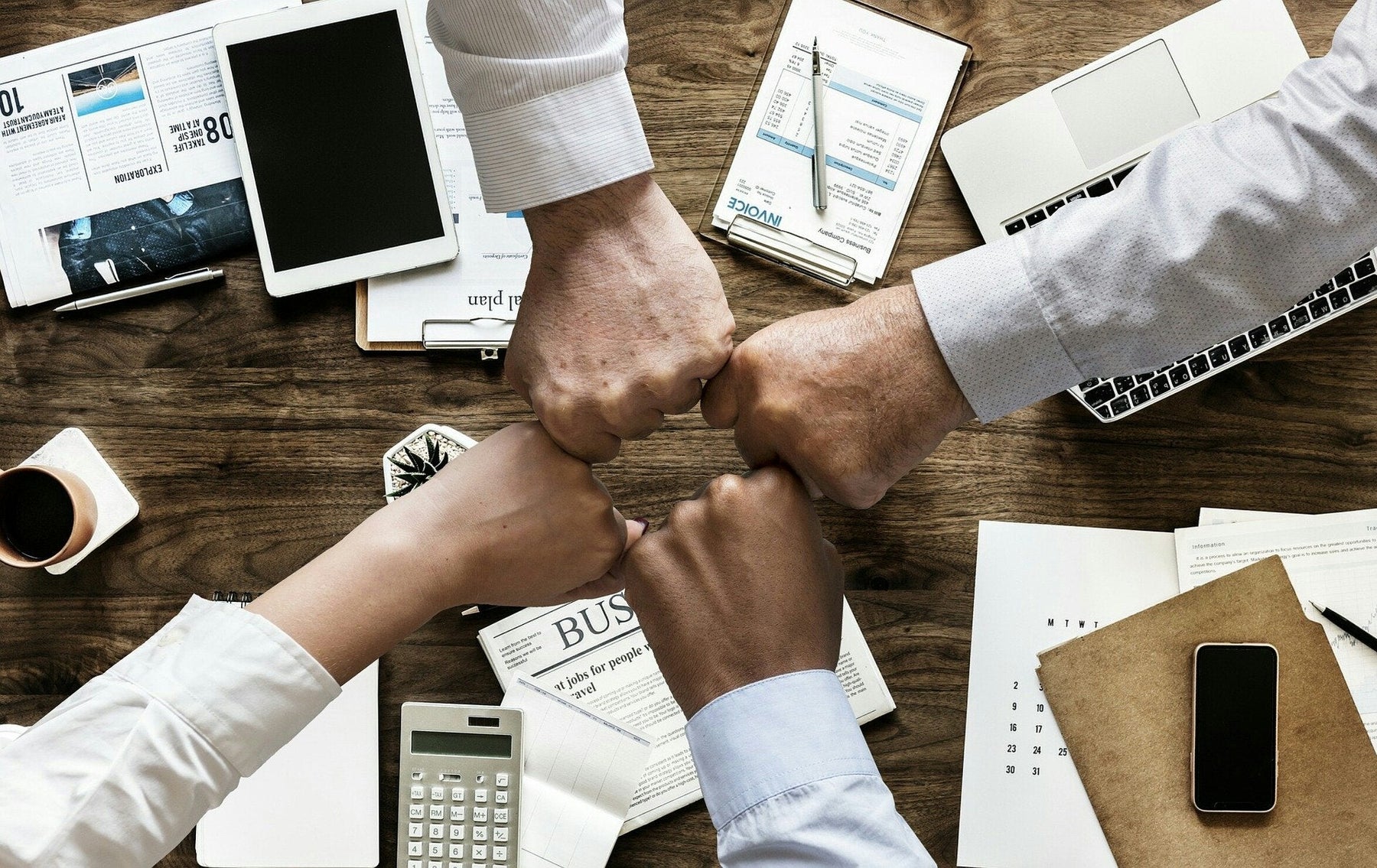 Four teammates in an office touching fists