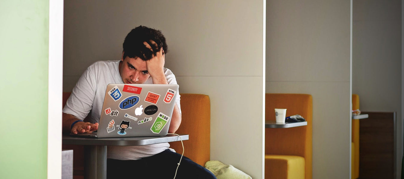 Young man stressing in a cubical watching his laptop