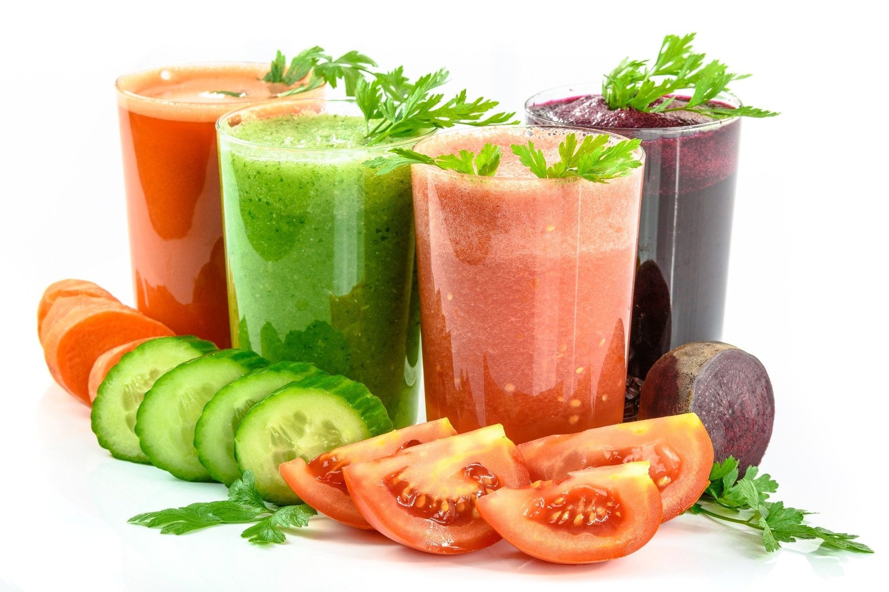 Multiple glasses of vegetable smoothie in red, green, pink and purple