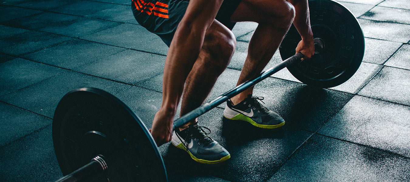 Man preparing to lift a barbell sitting on a black floor