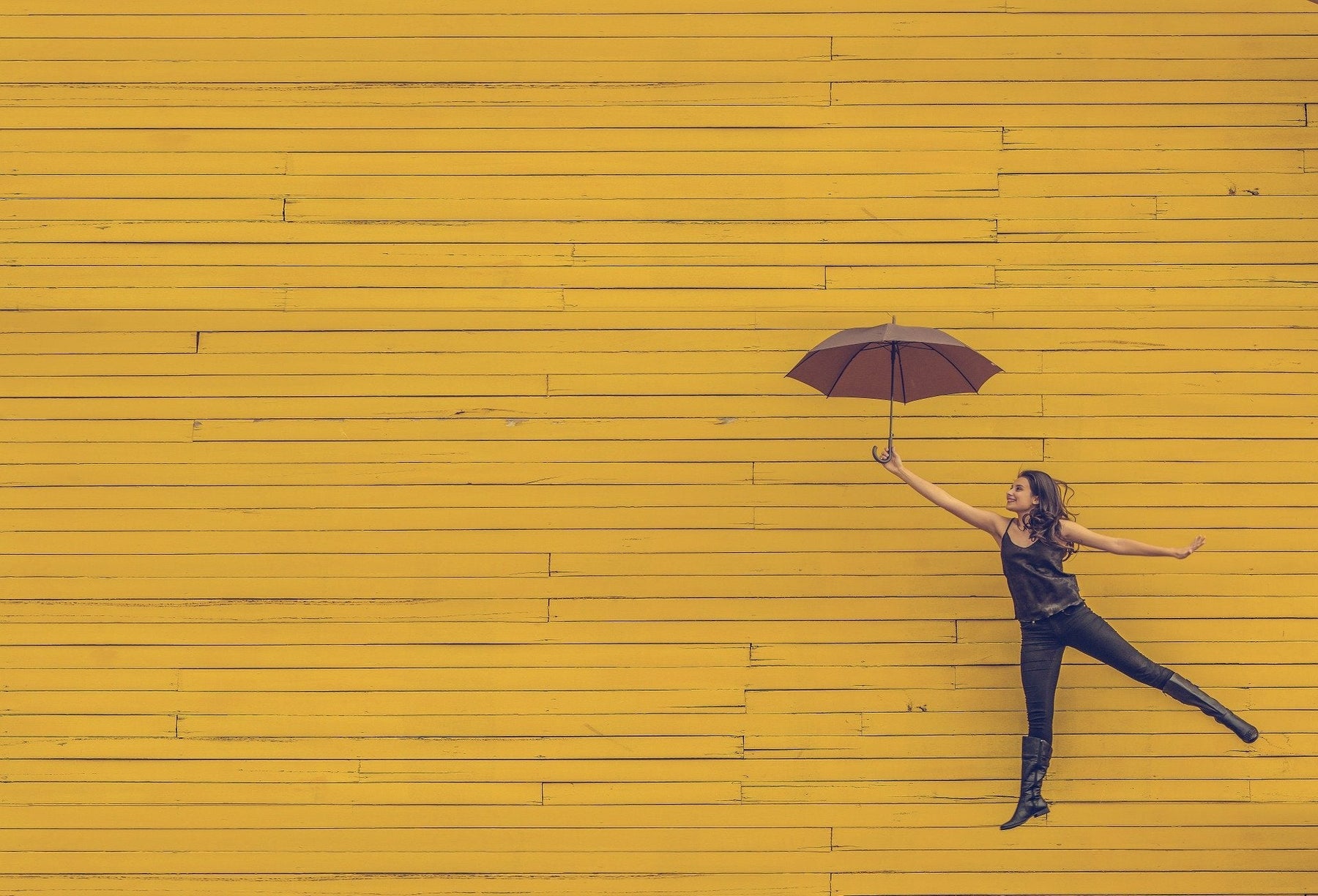 Woman holding umbrella with a foot pointed slightly up