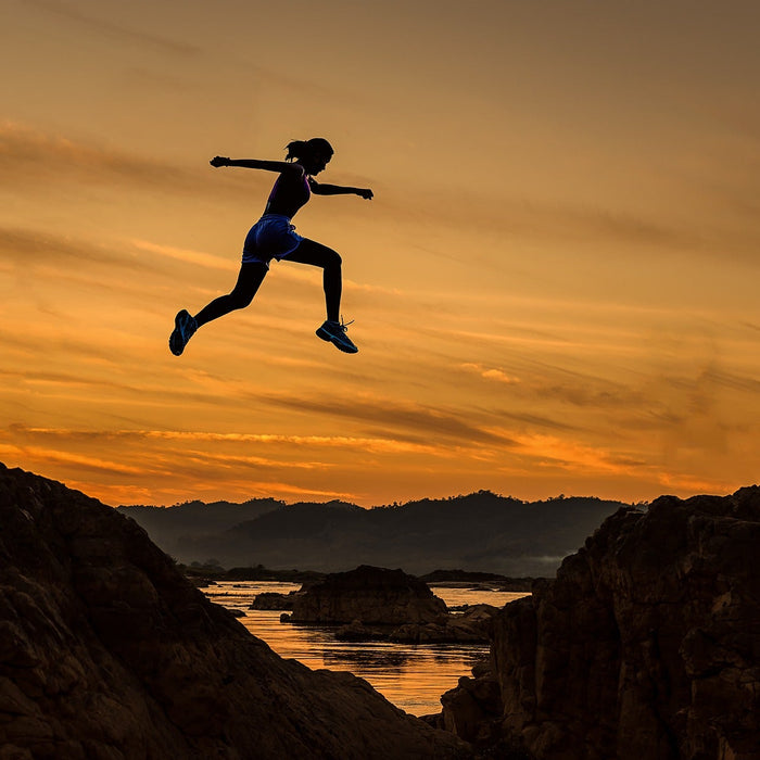 Woman jumping over hills during an evening