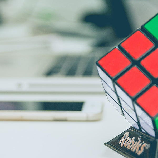 Unsolved rubick cube next to a phone and a laptop