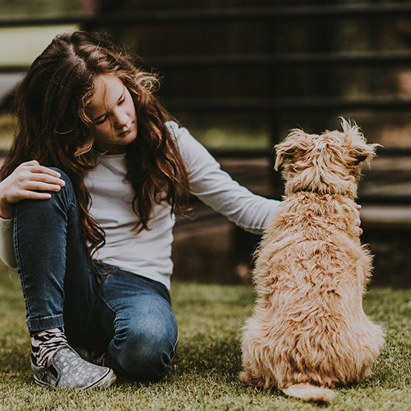 Woman petting a dog next to a fence