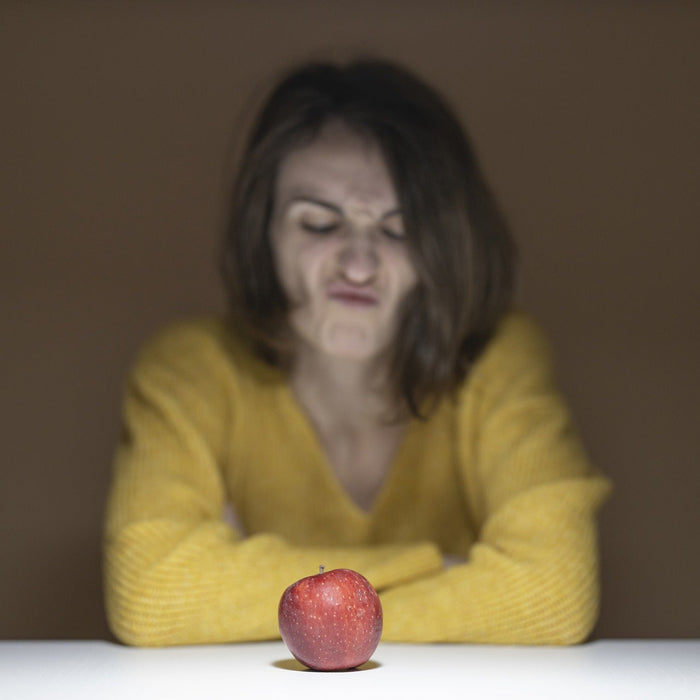 Angry woman looking down a red apple on a table