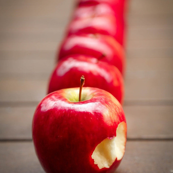 Red apples in line with the first one being bitten