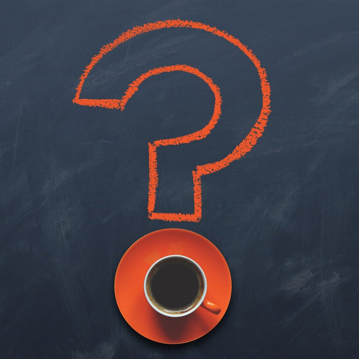 Question mark drown on a board with the dot being a cup of coffee on an orange plate