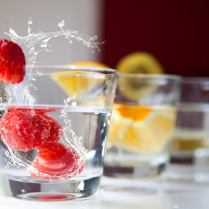 Raspberries dropped in a glass of water