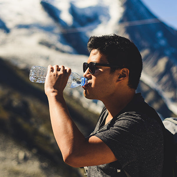 Thirsty man with black t-shirt and black backpack drinking water and hiking