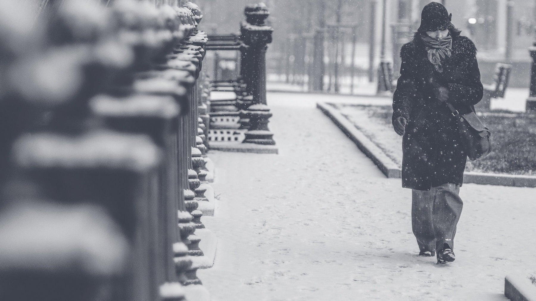 Woman walking down the street in a cold winter while snowing