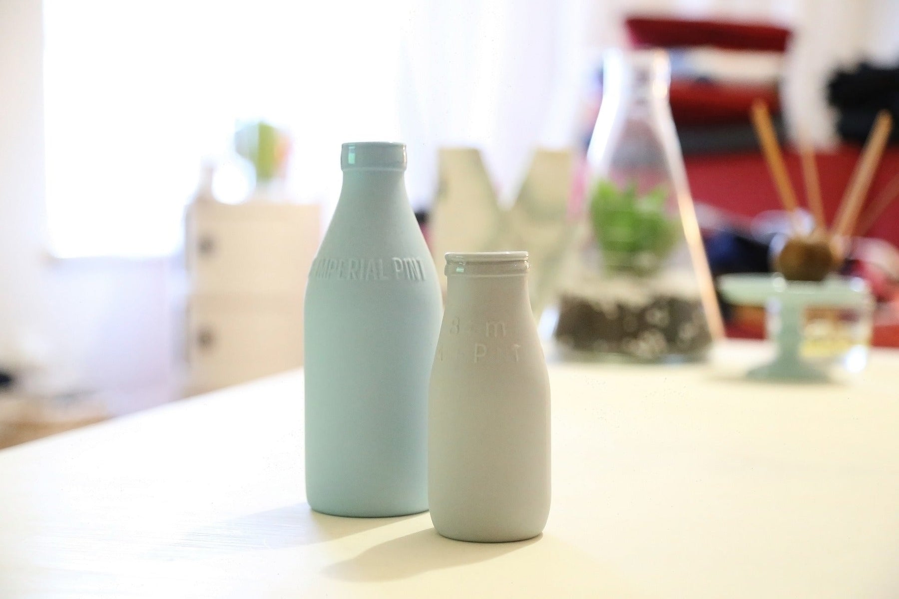 Two bottles of milk laying on a wooden table