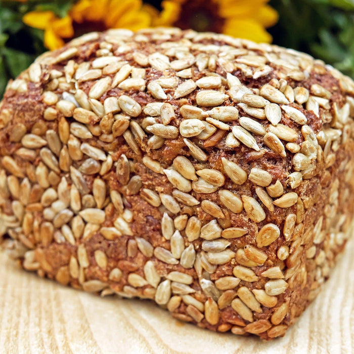 Bread with seeds on a wooden table and sunflowers in the back