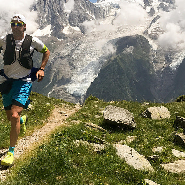 Man in blue shorts hiking and running on rocky mountain
