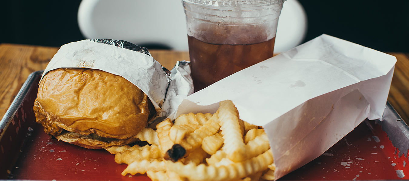 Fast food consisting of burger, fries and juice laying on a red plate