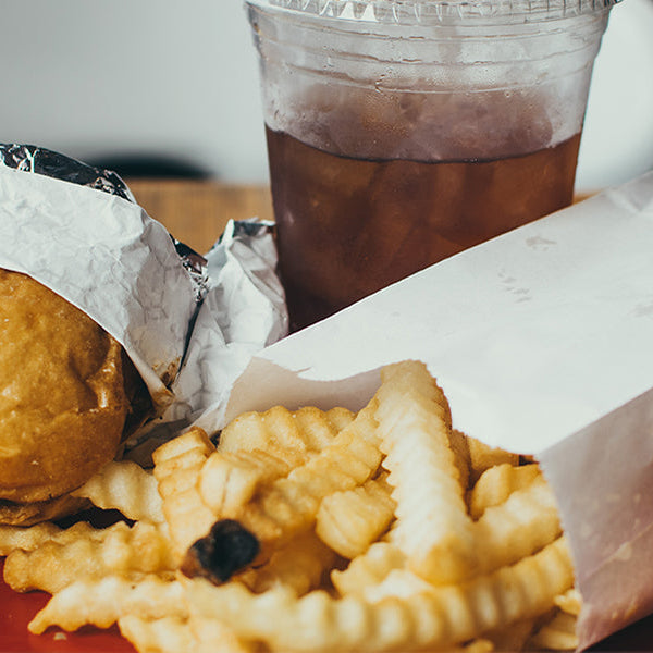 Fast food consisting of burger, fries and juice laying on a red plate