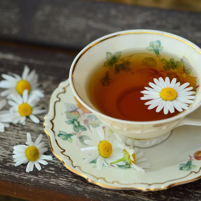 A cup of tea with flowers on a wooden surface