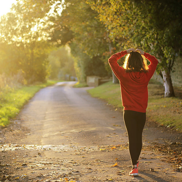 Girl in red sweater walking down a country road