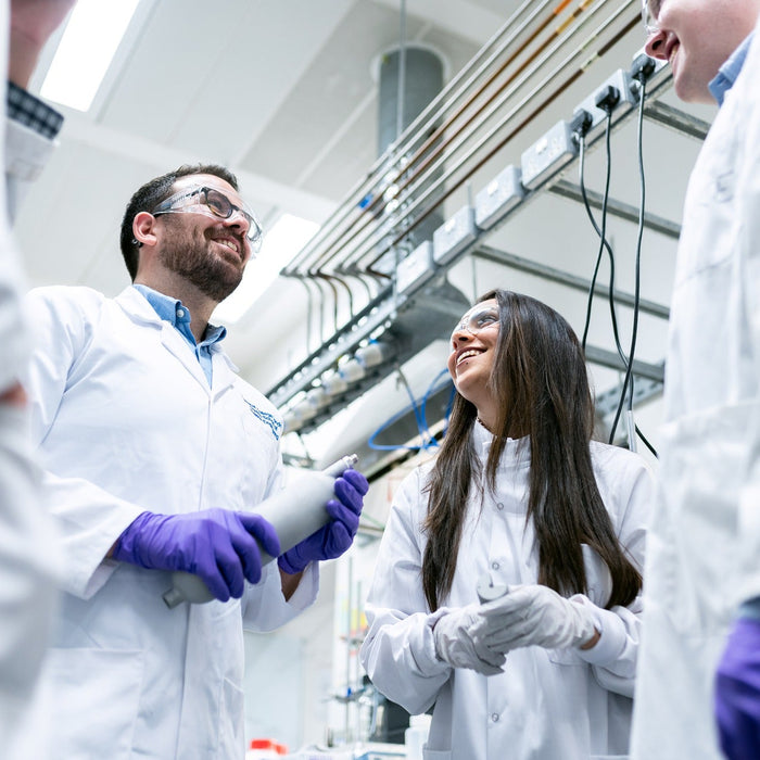 People in white with purple gloves discussing