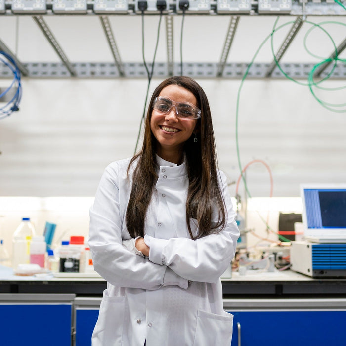 Woman in white with crossed hands smiling in laboratory
