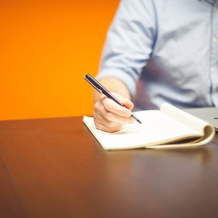 Man taking notes on a notebook over a wooden desk