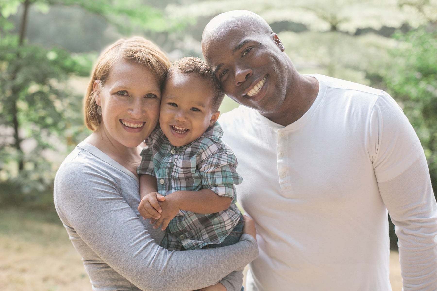 Happy man and woman holding their kid and smiling