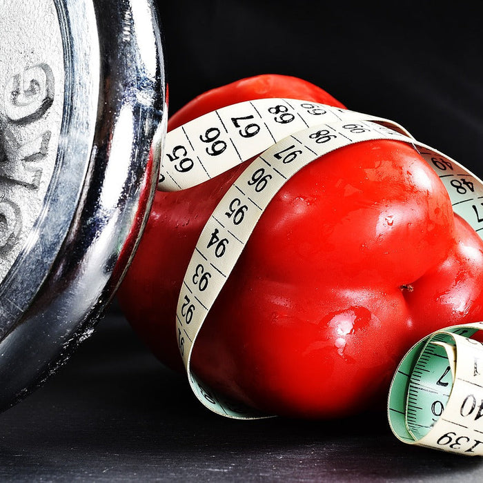 A dumbell next to a red bellpaper covered in a measurement band