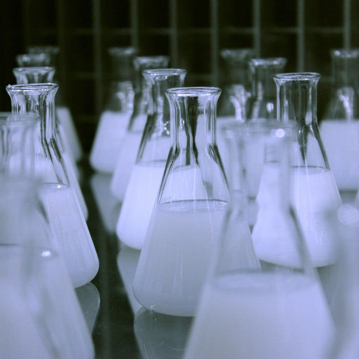 Multiple laboratory glasses with white liquid in line