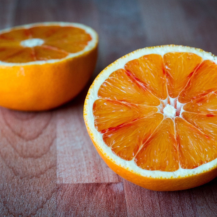 An orange cut in half over a wooden floor