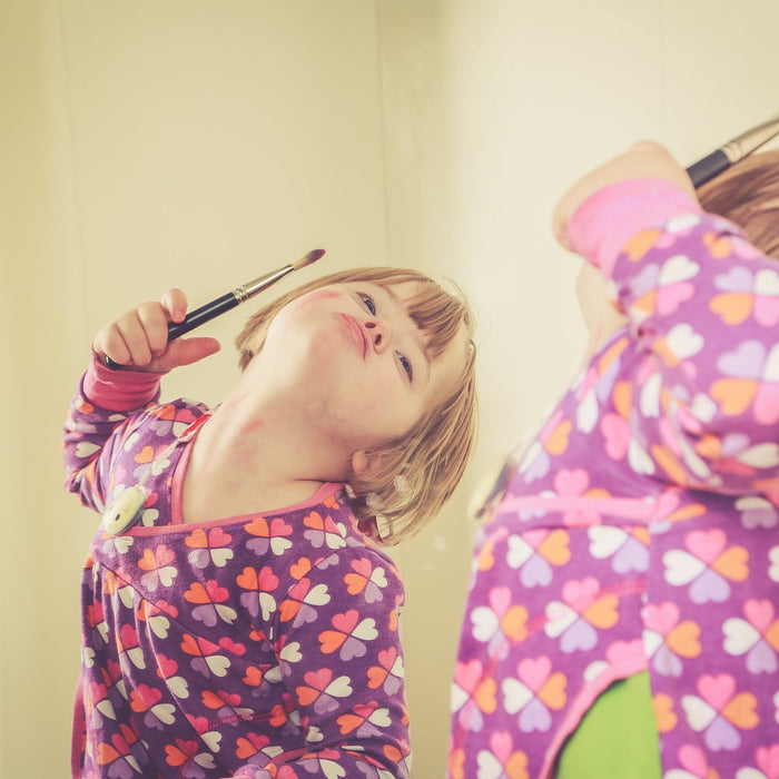 Girl in pajamas making faces in the mirror