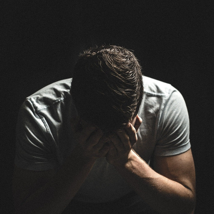 Man in a t-shirt covering face with his palms